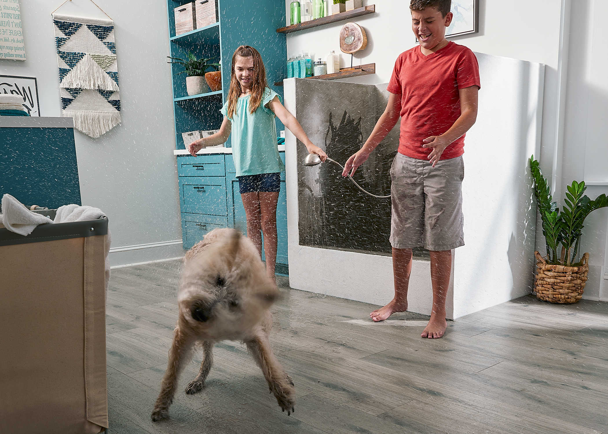 greige waterproof hybrid resilient floor in laundry room and dog washing station with pre teens in red shirt and blue shirt washing tan and white dog while dog shakes water all over floor