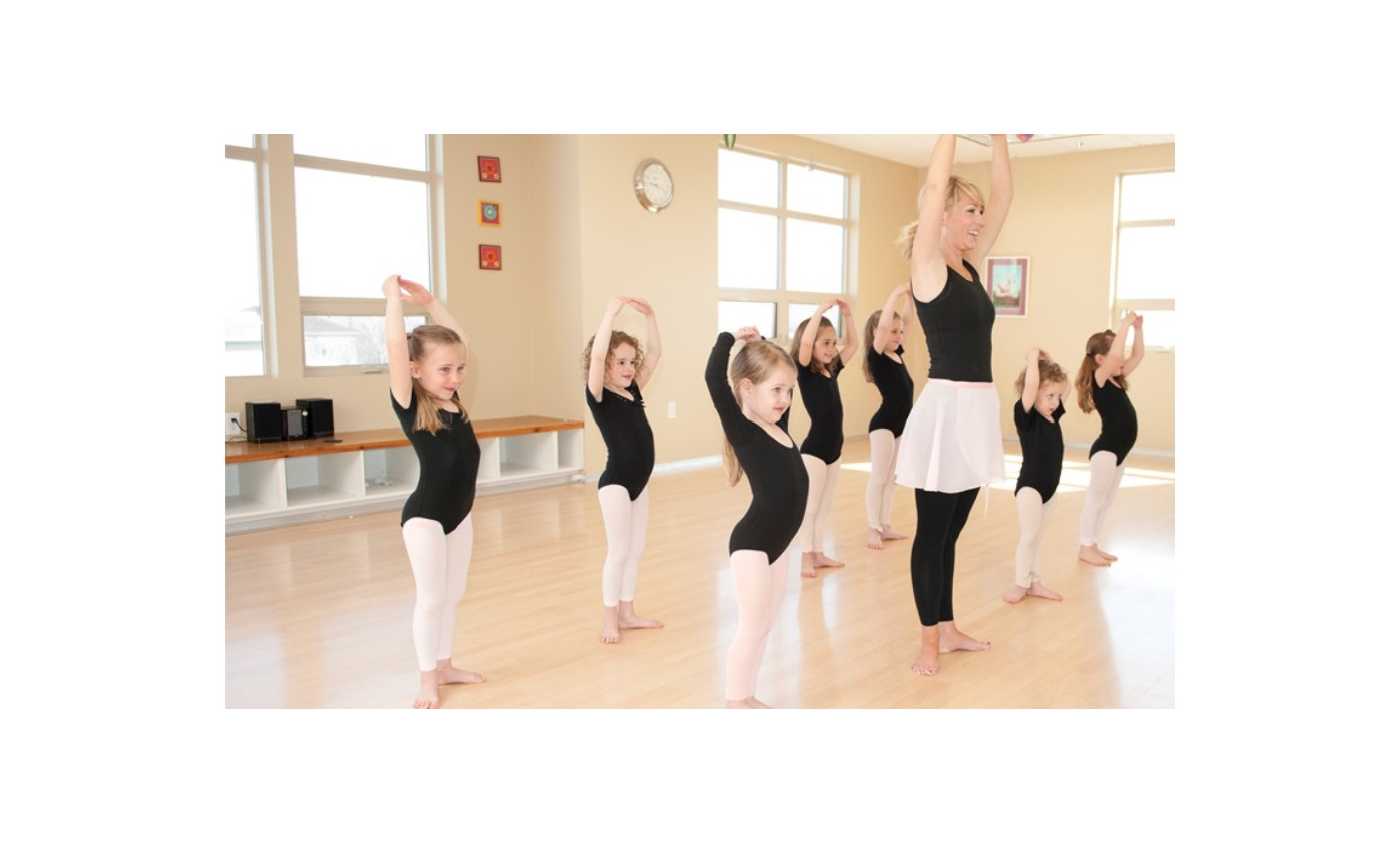 young children with instructor in ballet class on light blonde wood floor