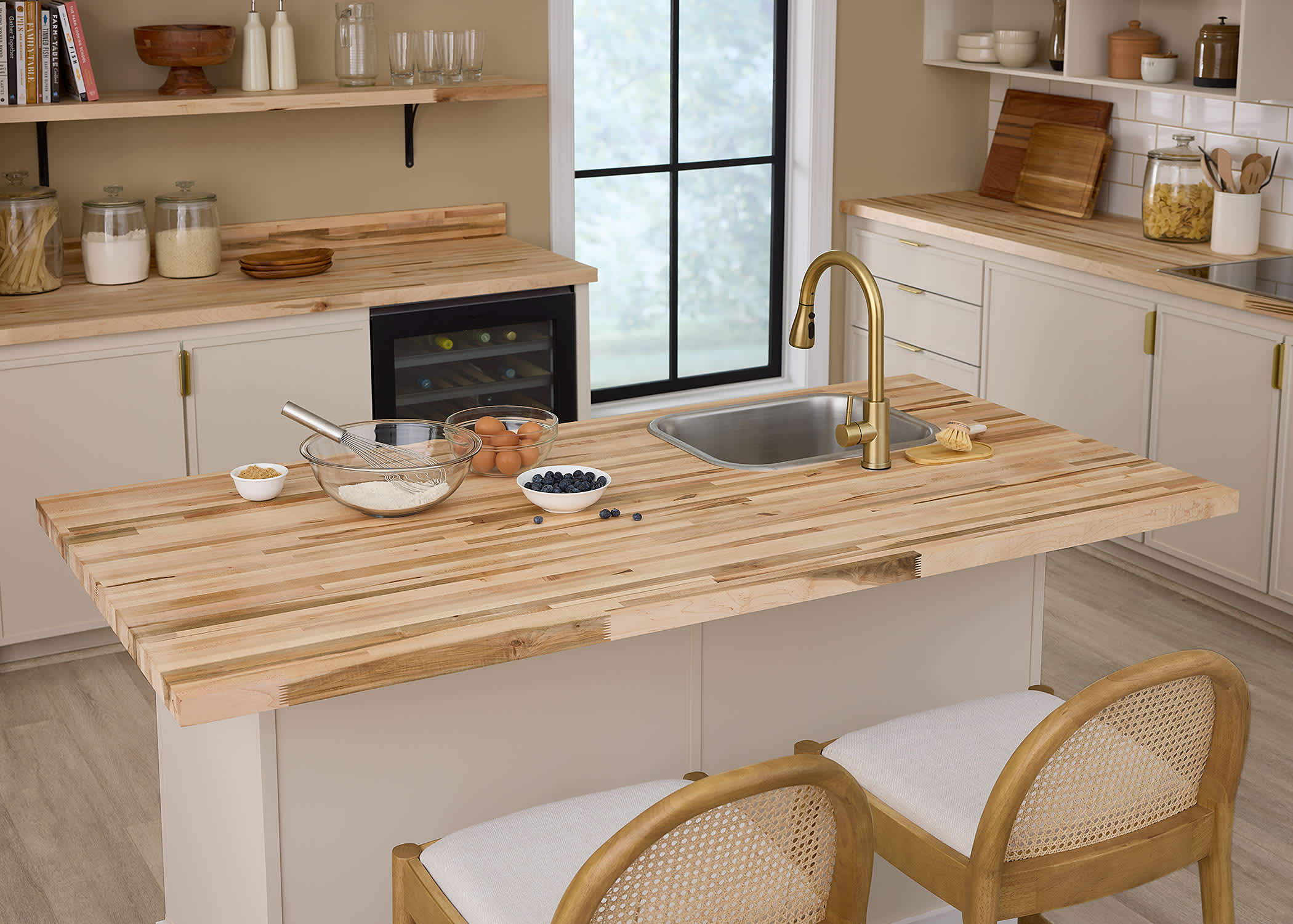 butcher block counters in kitchen with drop in sink and brass single handle faucet plus rattan armless bar stools