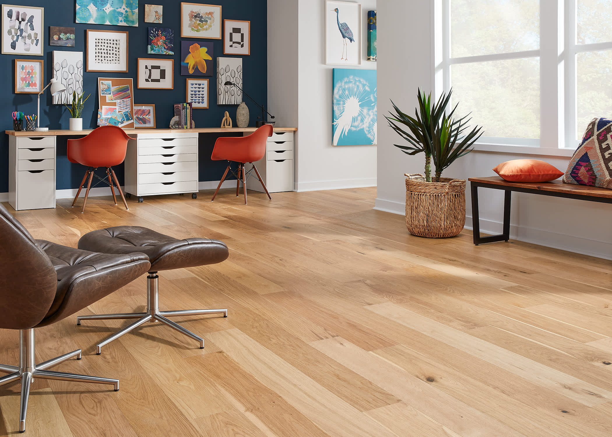 multi toned blonde engineered hardwood floor in office with dark brown leather chair and orange desk chairs