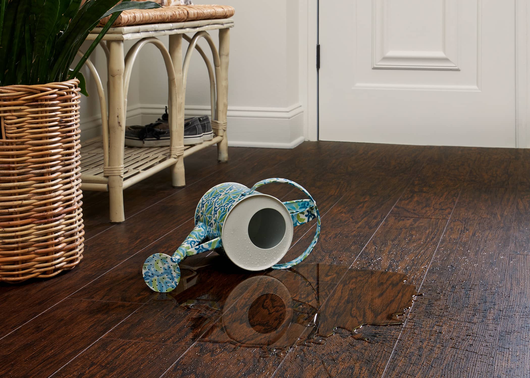 Shoreline Hickory Waterproof Laminate Flooring with watering can spilling water onto the floor