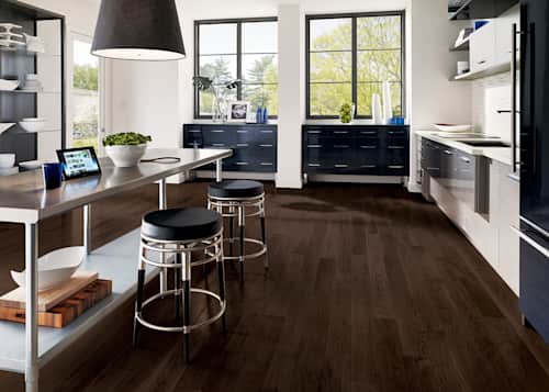dark brown solid hardwood floor in kitchen with metal island and sleek gray cabinets