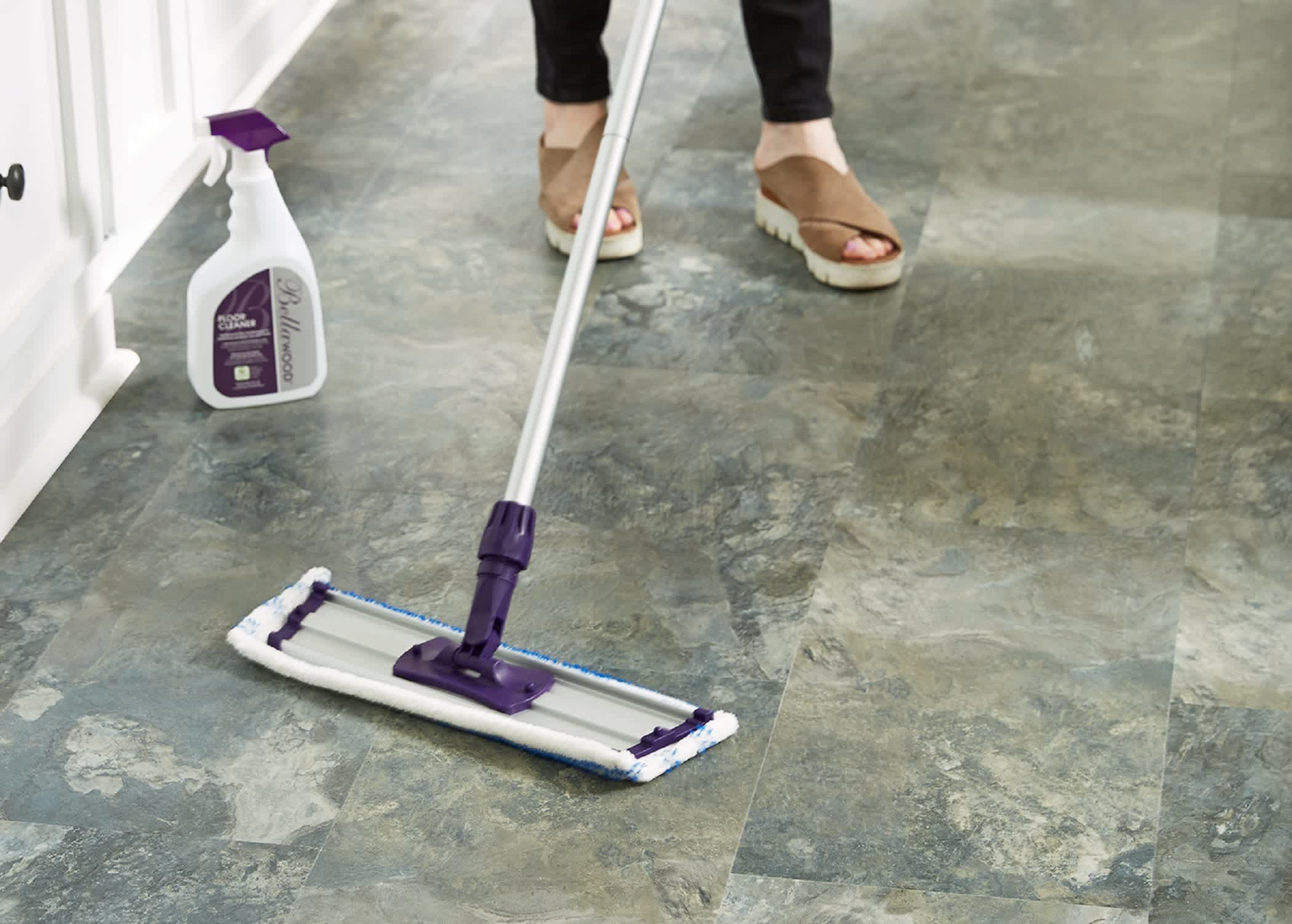 person using bellawood wet mop pad on waterproof vinyl floor in kitchen with spray bottle on floor