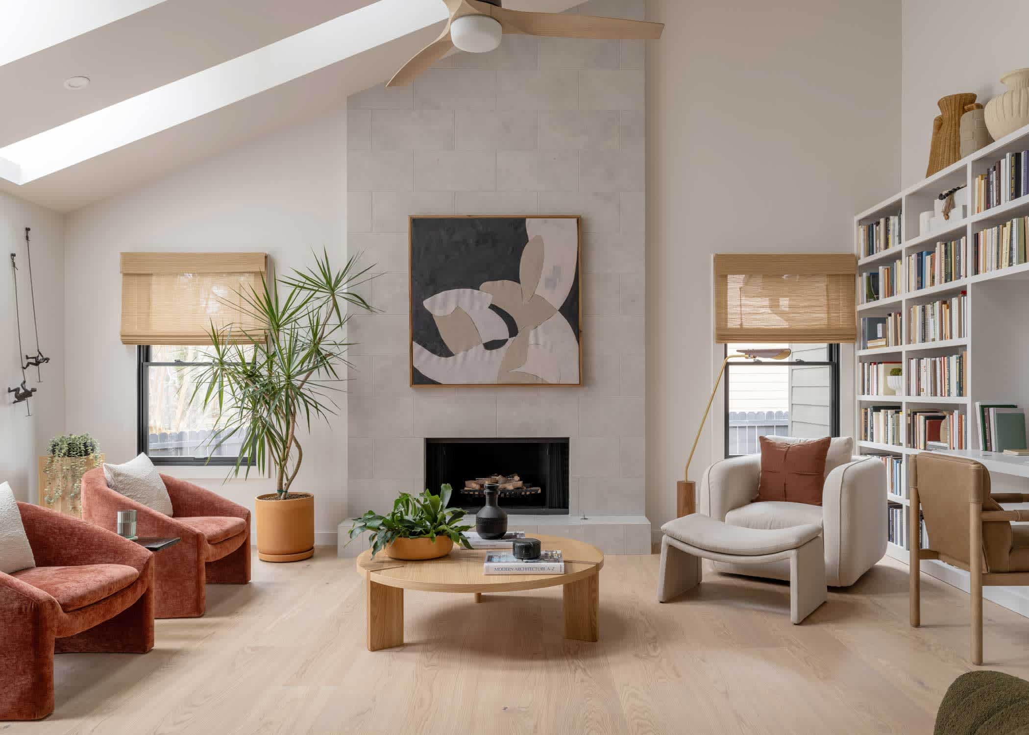 Lagan River White Oak Engineered Hardwood Flooring 2024 HGTV Smart Home living room with Cemento Lucido Porcelain tile on fireplace face and dark rust upholstered chairs plus beige upholstered chair and built in bookcases