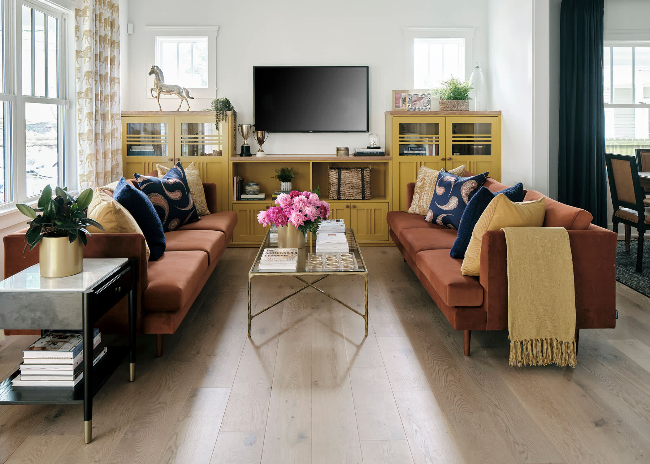 Vienna White Oak Engineered Hardwood Flooring in living room of HGTV 2023 Urban Oasis Home with rust velvet matching sofas plus muted yellow throw and built in bookcases