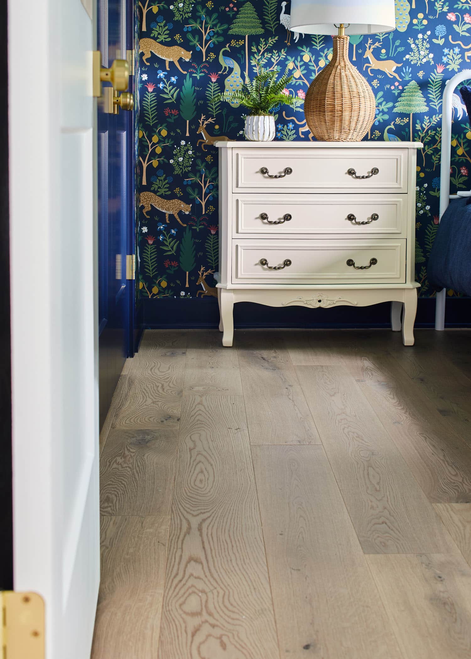 Valberg White Oak Engineered Hardwood Flooring in bedroom of HGTV 2023 Urban Oasis Home with blue animal and floral wallpaper plus cream side table and rattan table lamp
