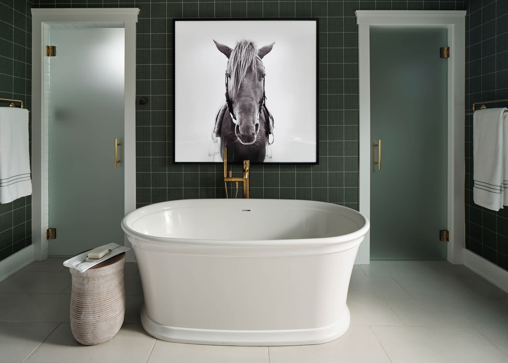 Regency Pearl Porcelain Tile Flooring in primary bathroom of HGTV 2023 Urban Oasis Home with white freestanding oval bathtub plus frosted glass doors on either side and equestrian artwork on wall above tub
