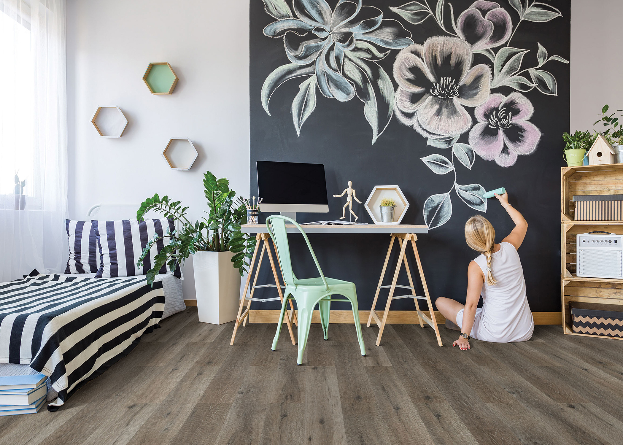 a girl draws flowers on the wall with wood look cork flooring in the bedroom
