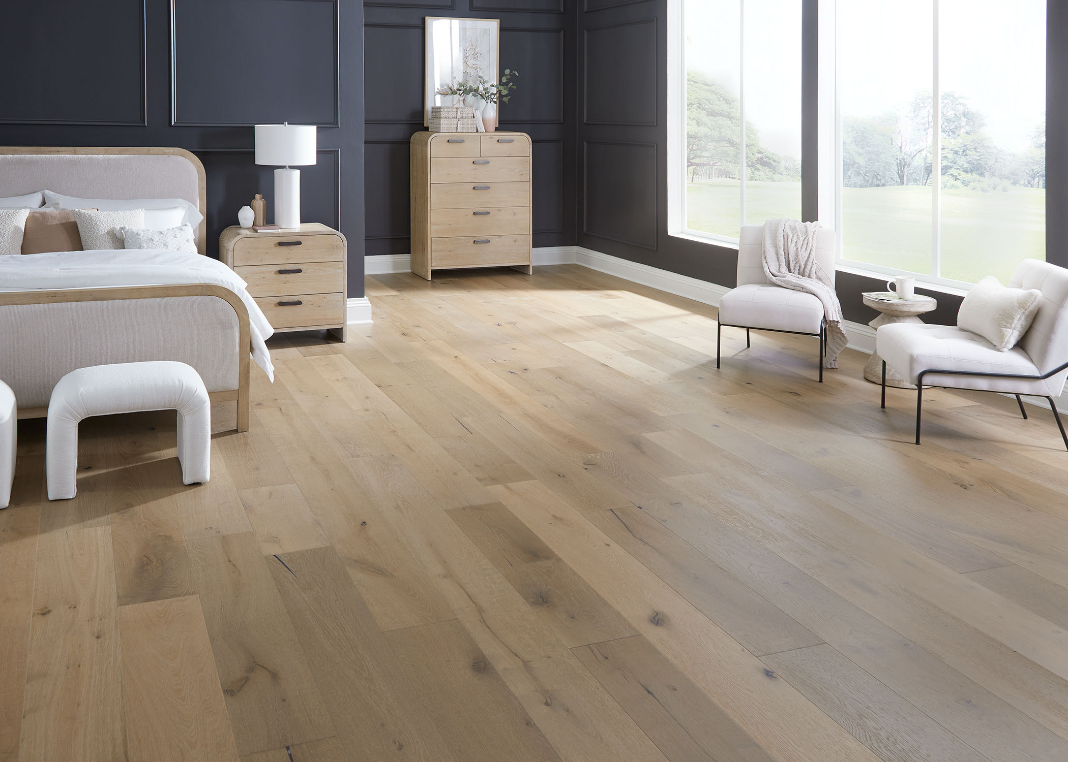 blonde engineered hardwood floor in bedroom with black walls plus white upholstered armless chairs and blonde wood furnishings
