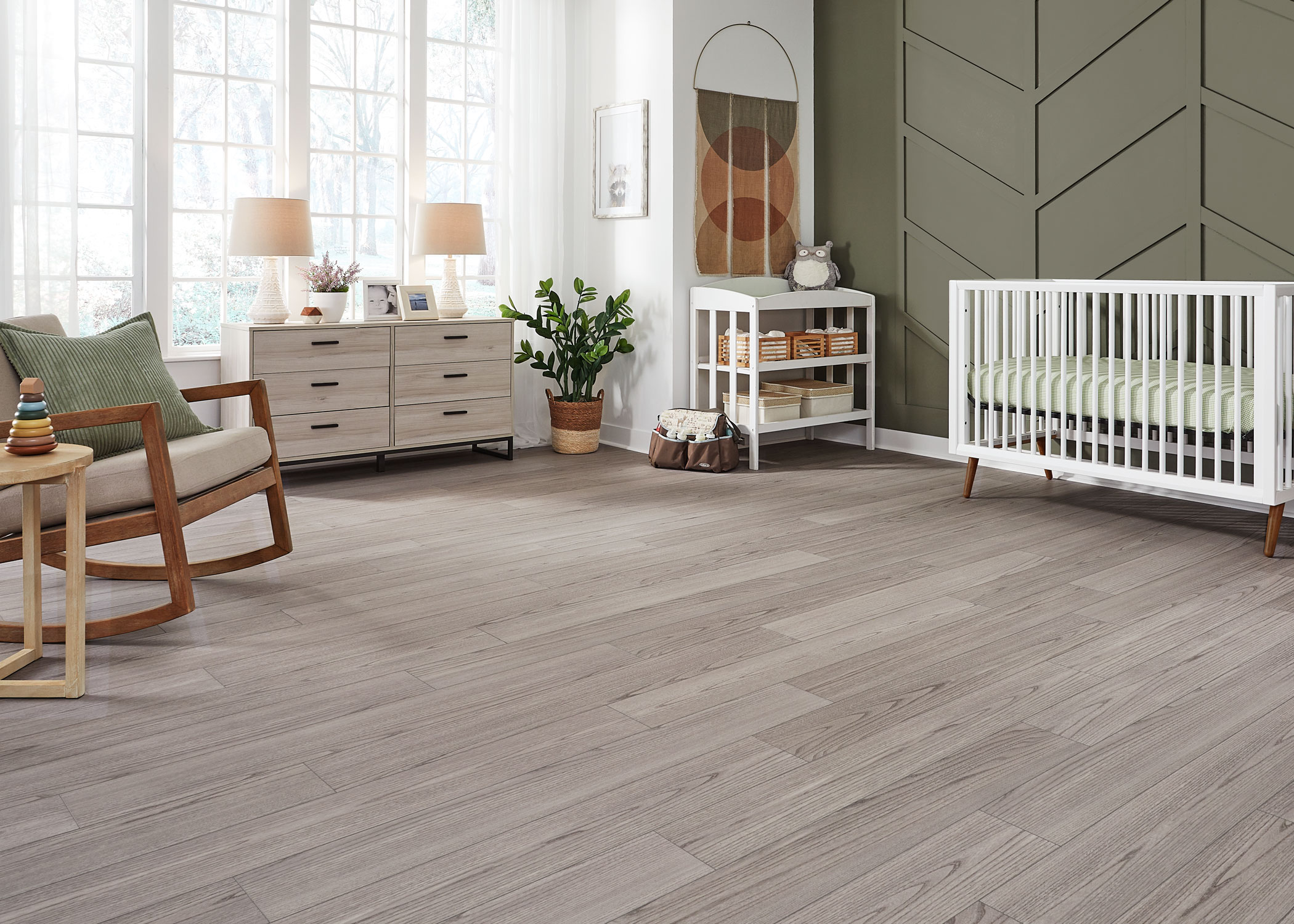 beige waterproof rigid vinyl plank floor in nursery with green accent wall plus white crib and wood rocking chair