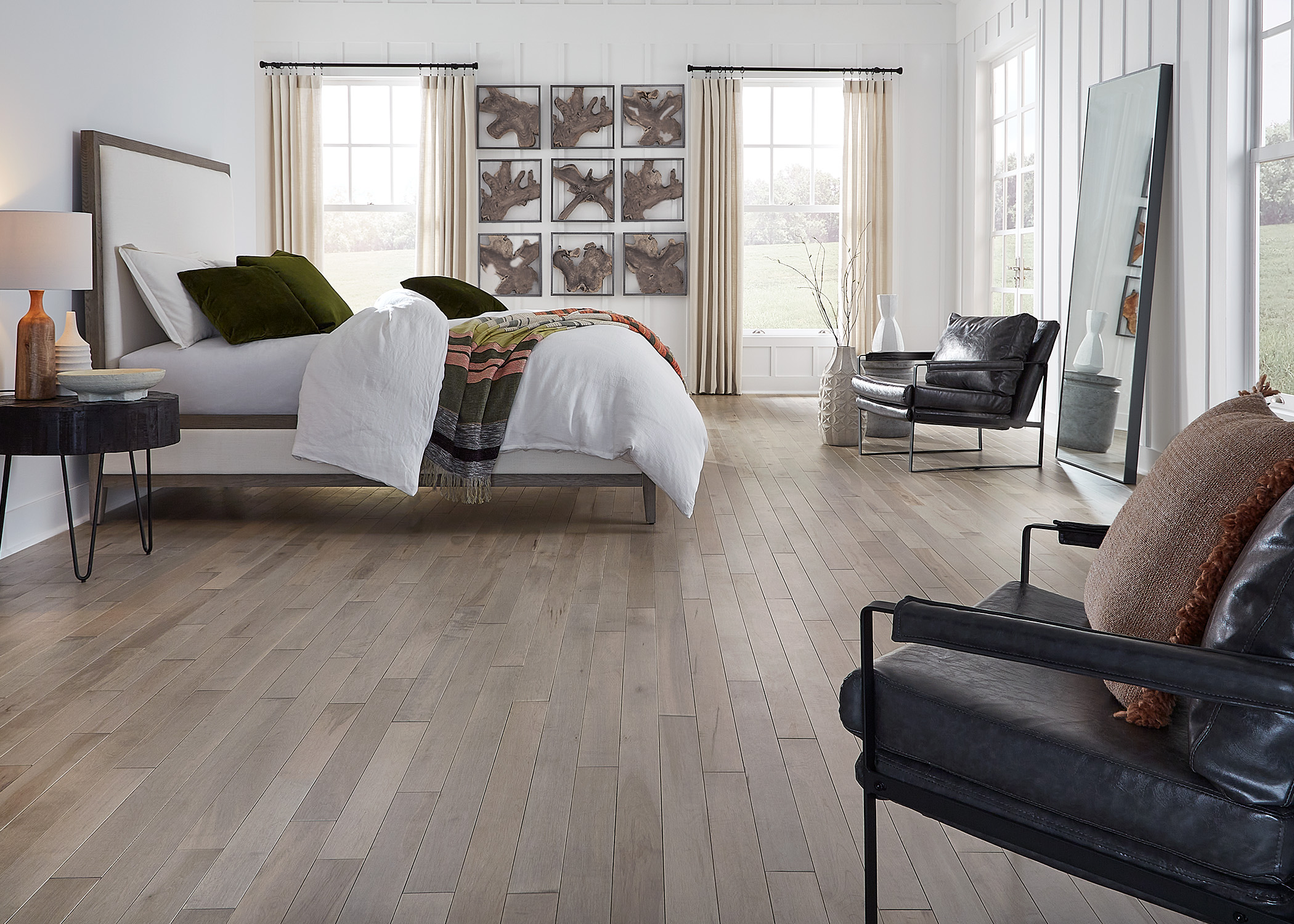 medium brown solid hardwood floor in bedroom with white bedding and dark brown leather chairs