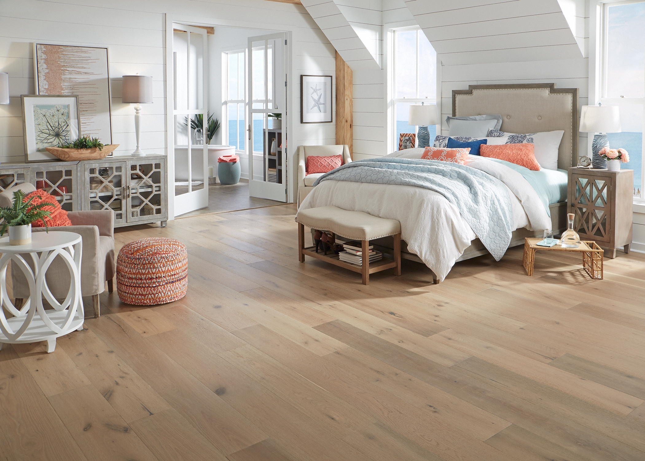 blonde distressed engineered hardwood floor in bedroom with beige headboard and pale green and orange bedding plus white furniture and shiplap on walls