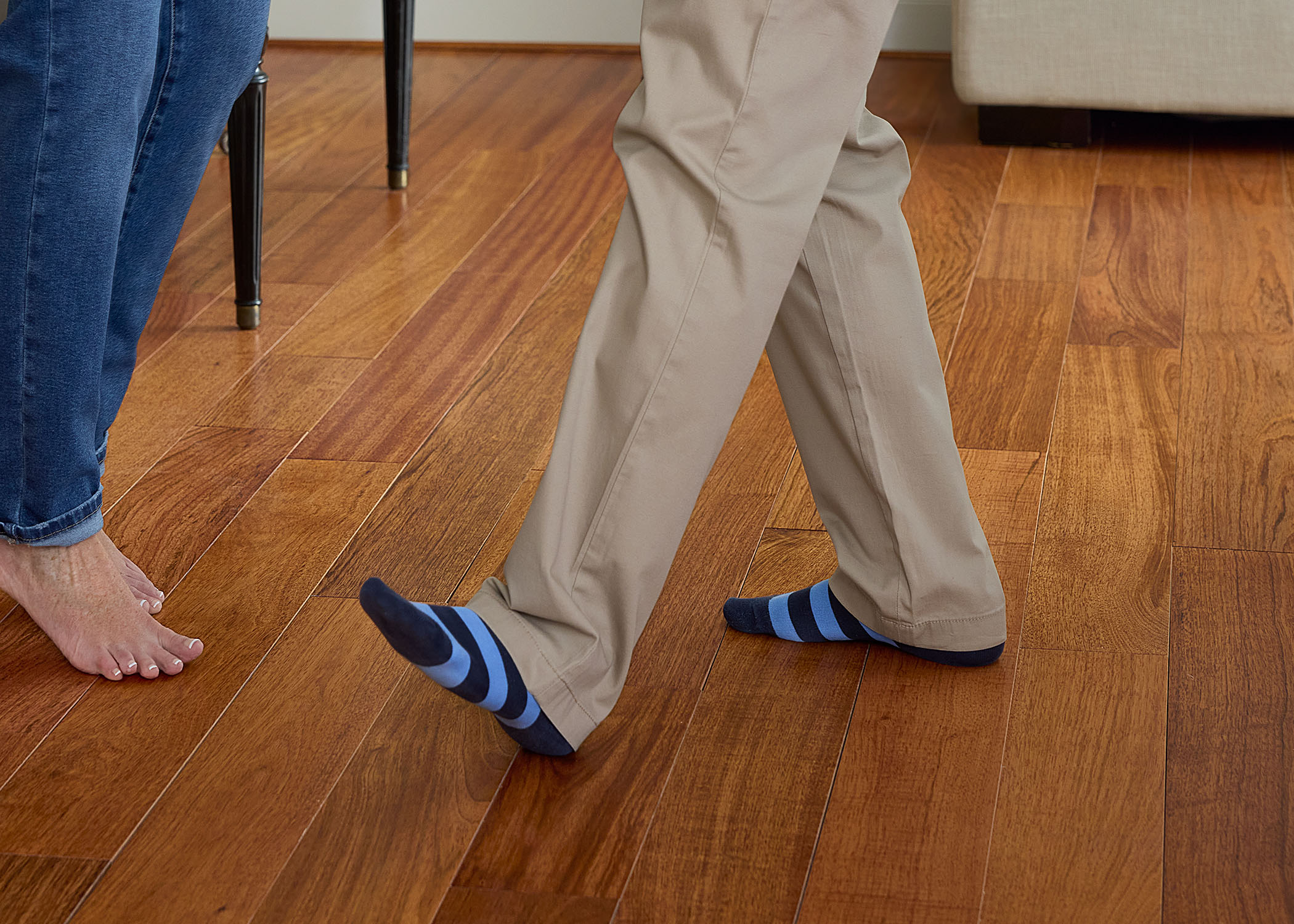 reddish brown solid hardwood floor with closeup of two people dancing on floor with one person wearing blue striped socks and the other barefoot