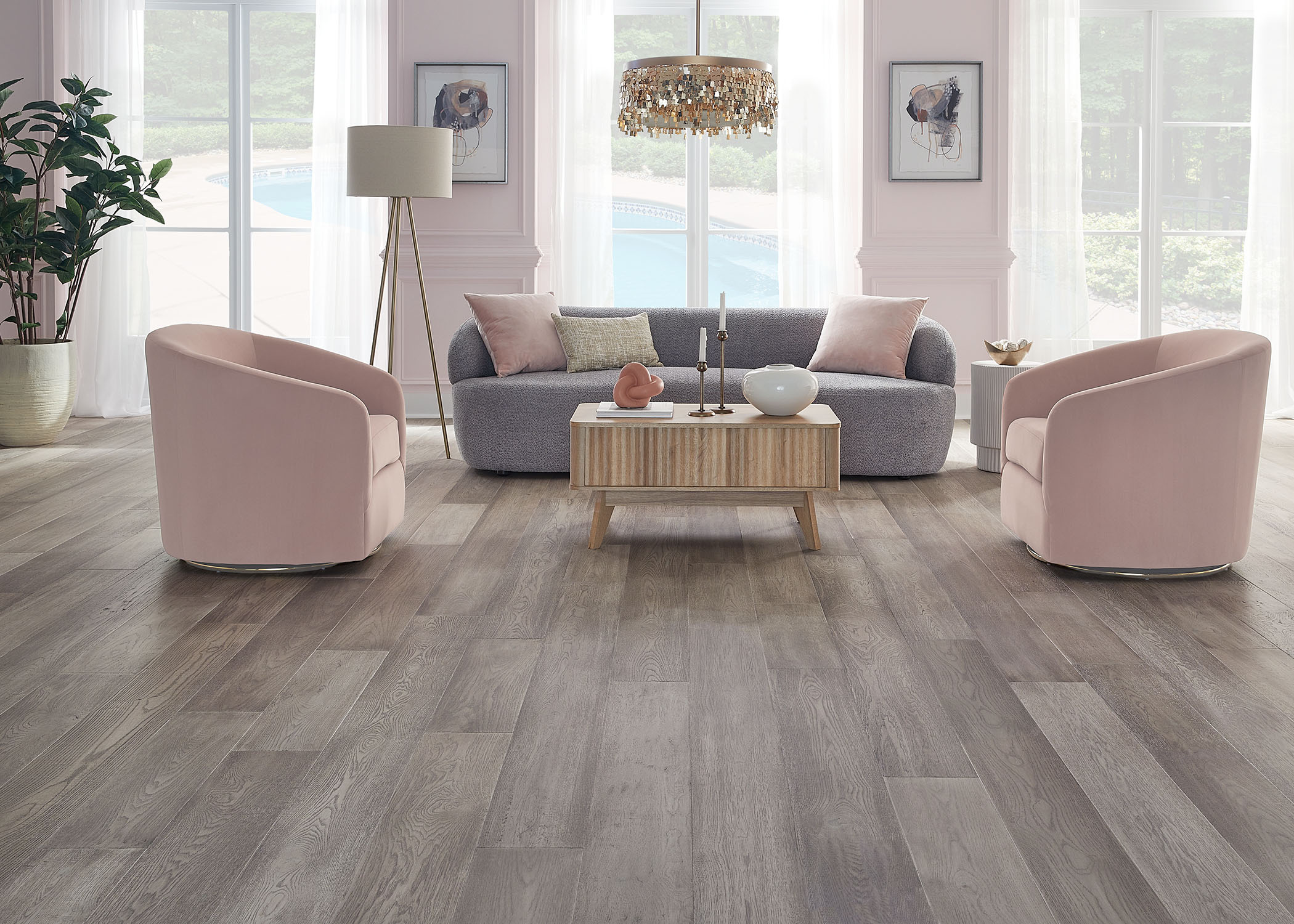 light gray engineered hardwood floor in living room with gray sofa with pale pink accent pillows and pink barrel chairs plus blonde wood cocktail table