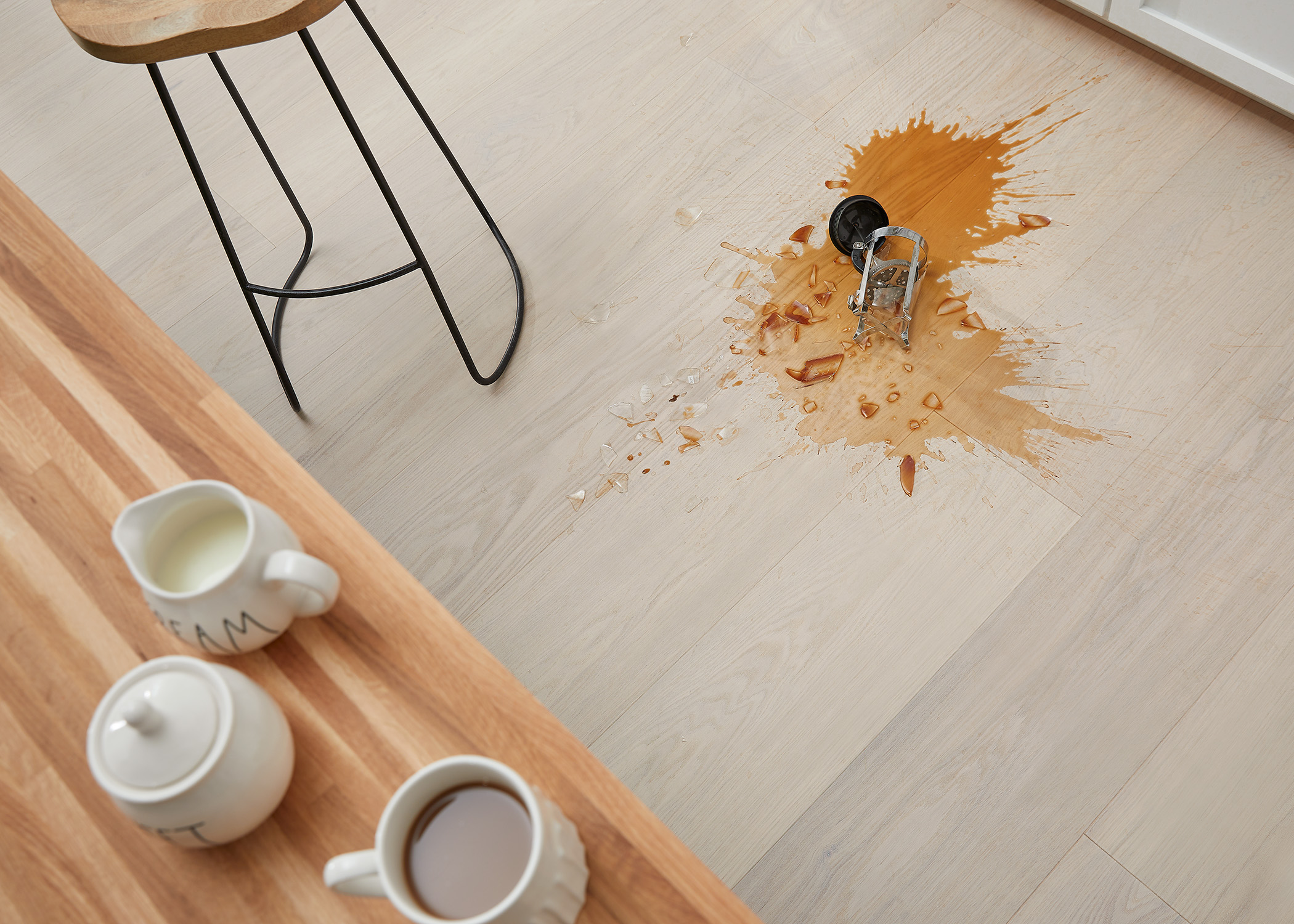 white washed water resistant engineered hardwood floor in kitchen with spilled coffee on floor and broken French press