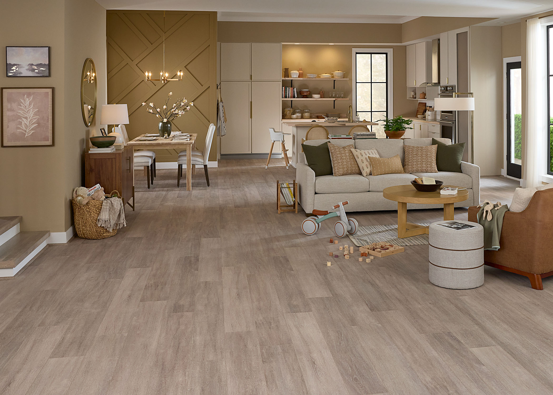 light brown waterproof rigid vinyl plank floor in open concept living, dining and kitchen with beige sofa and caramel accent chair plus wood dining table with cream chairs and white kitchen cabinets with butcher block counters