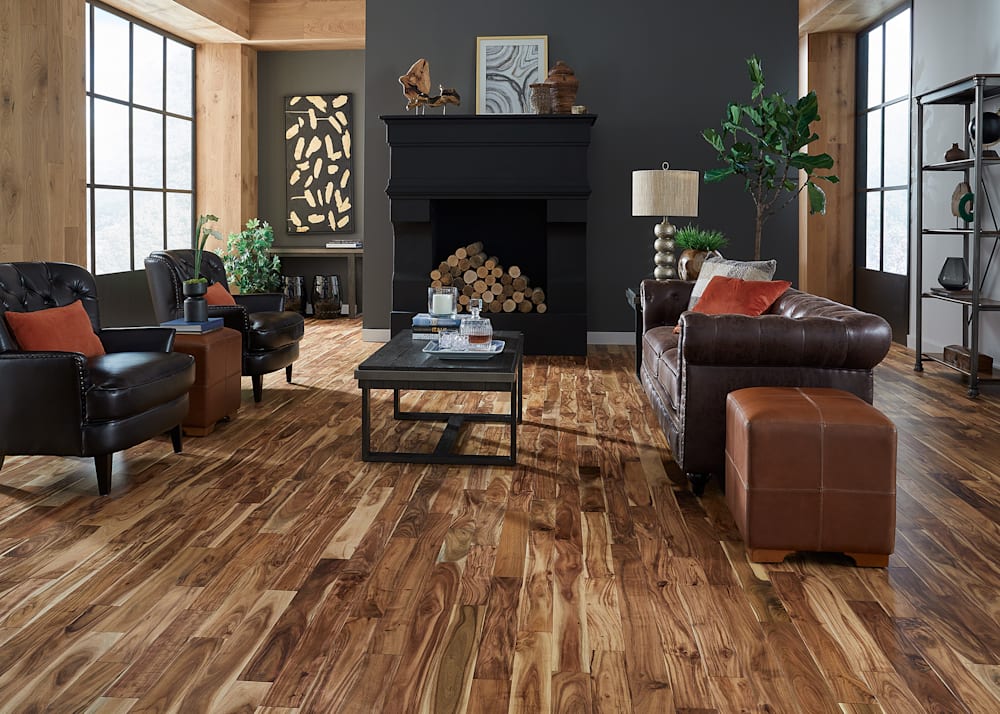 3/4 in. x 3.6 in Tobacco Road Acacia Solid Hardwood Flooring in living room with dark brown leather furniture and black fireplace