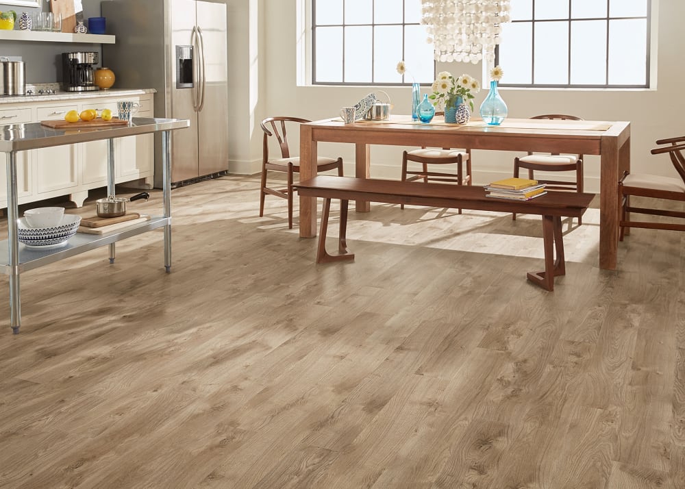 5mm Riverwalk Oak Luxury Vinyl Plank Flooring in open concept dining and kitchen with light wood dining table and bench seat plus wood chairs and shell chandelier above plus stainless steel island and white kitchen cabinets and stainless steel refrigerator