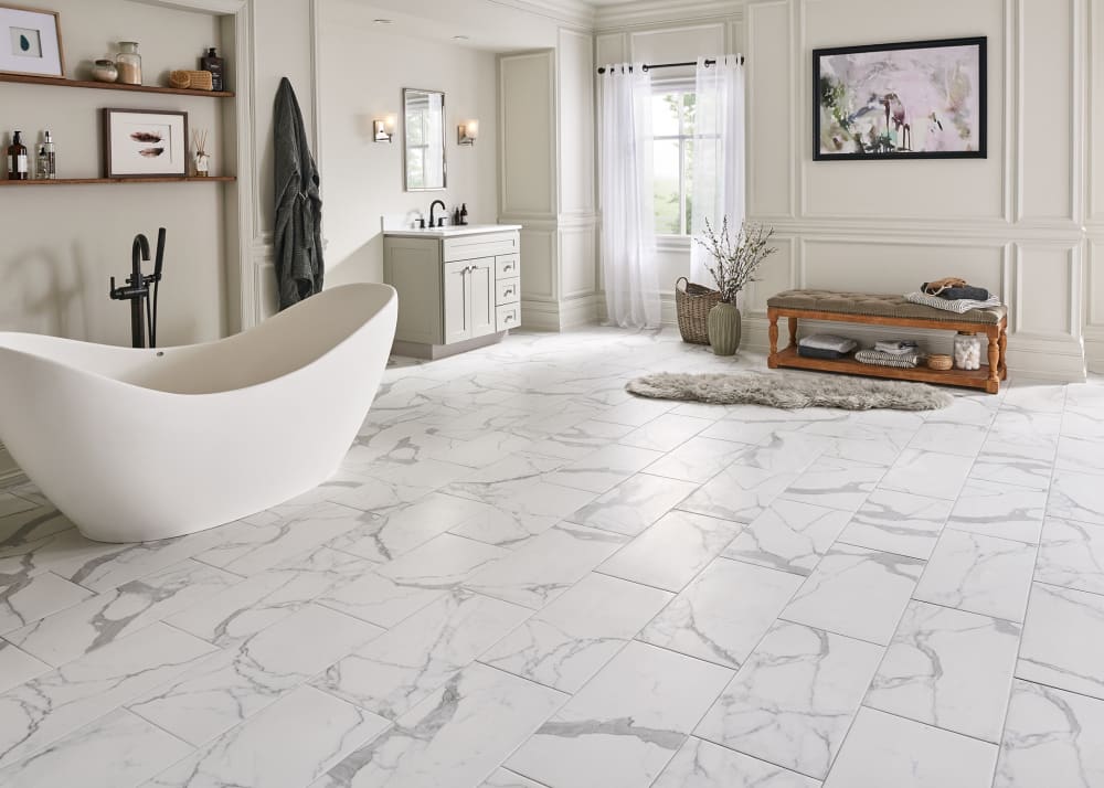 24 in. x 12 in. Bianca Carrara Porcelain Tile in bathroom with freestanding tub plus floating shelves above and off white walls