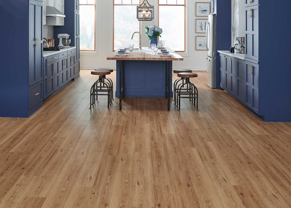 7mm with Pad Honey Mead Oak Rigid Vinyl Plank Flooring in kitchen with blue floor to ceiling cabinets plus butcher block island and white countertops