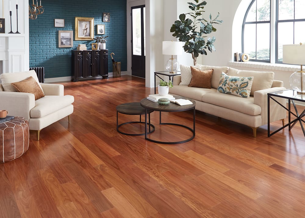 1/2 in. x 5 1/8 in. Select Santos Mahogany Engineered Hardwood Flooring in living room and entry with cream upholstered furnishings plus teal painted brick all with artwork collage and dark brown accessories