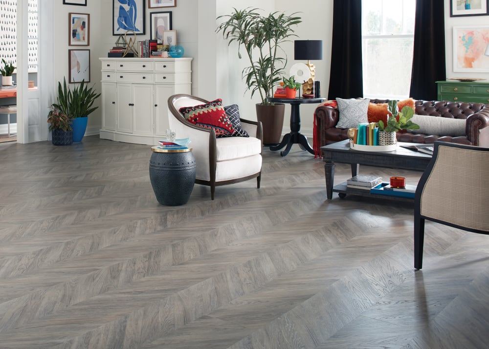 6mm Pacific Coast Oak Chevron Rigid Vinyl Plank Flooring in living room with white barrel chair and dark brown leather sofa