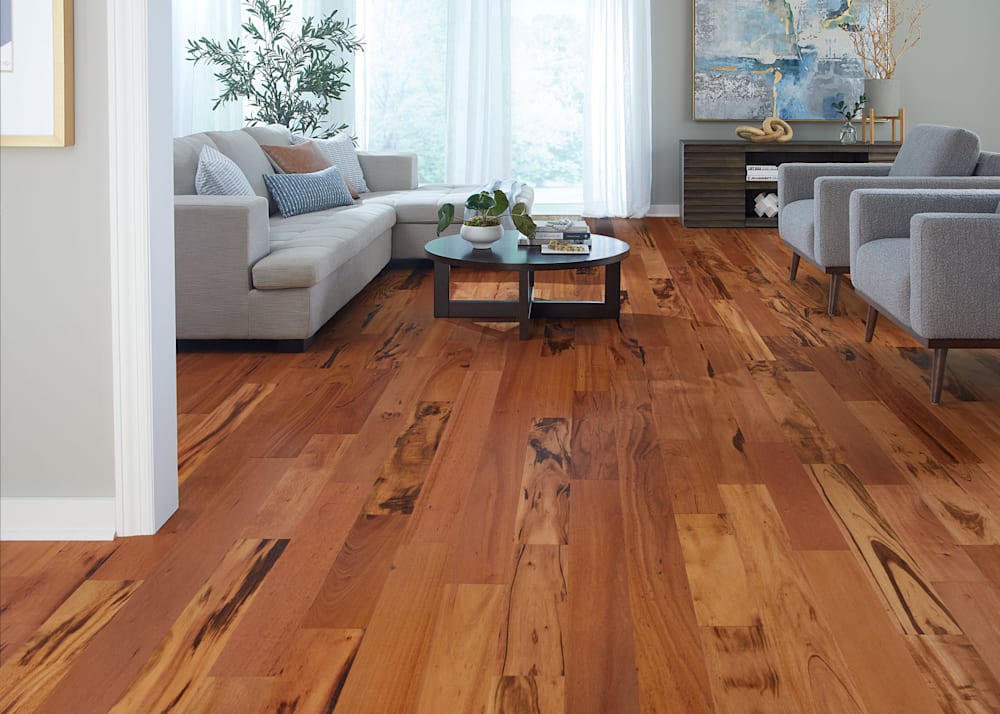 1/2 in. x 5 1/8 in. Select Brazilian Koa Engineered Hardwood Flooring in living room with gray upholstered furniture with dark brown accent tables and blue and gold artwork