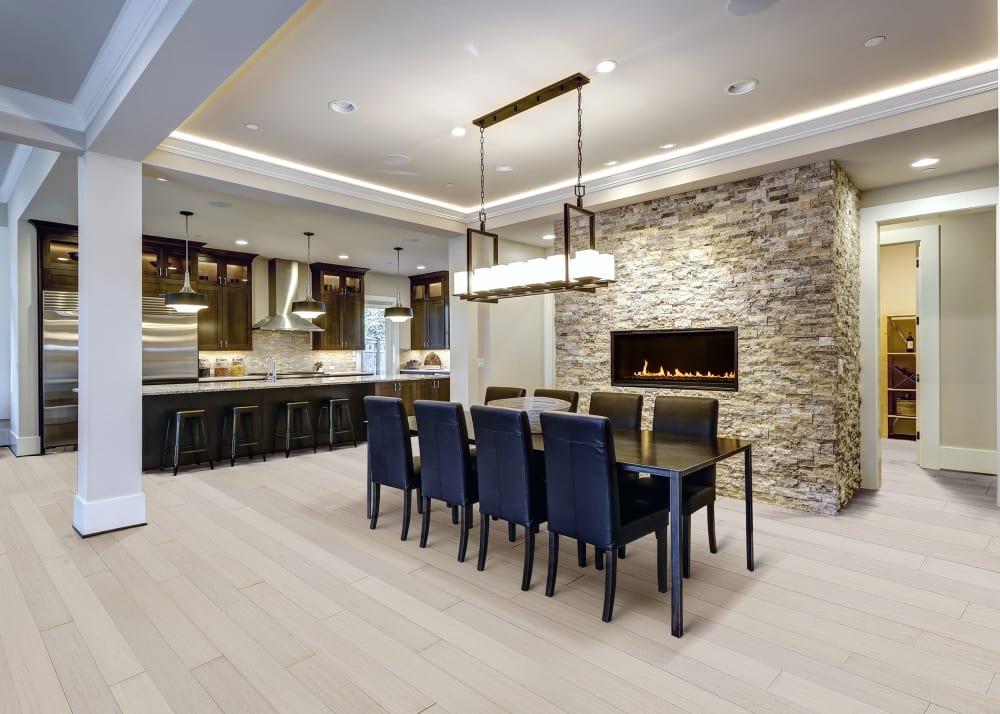 Saint Anton Strand Extra Wide Plank Engineered Bamboo Flooring in open concept kitchen and dining room with black dining table and chairs plus stone fireplace and dark brown kitchen cabinets