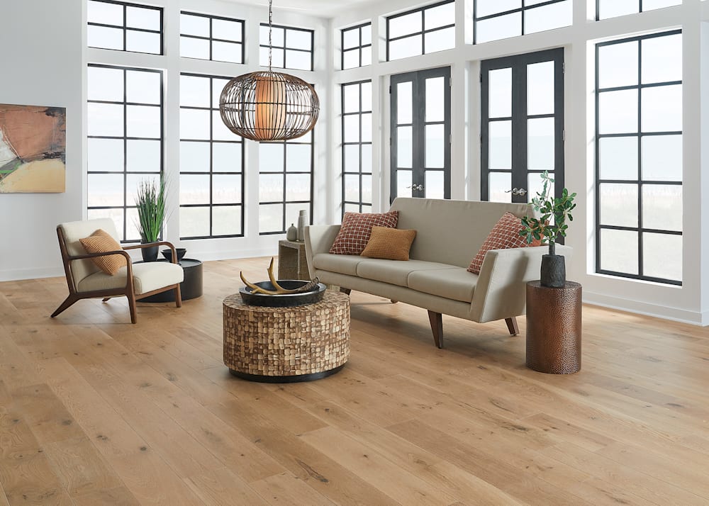 5/8 in. x 7.5 in. Amsterdam White Oak Engineered Hardwood Flooring in living room with beige sofa and round wooden coffee table plus rust colored pillows and bronze metal side table