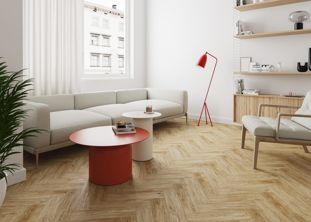 12mm+pad Melrose Herringbone Water-Resistant Laminate Flooring in living room with oversized crane sofa plus light wood floating bookshelf and cream upholstered accent chair with red round coffee table