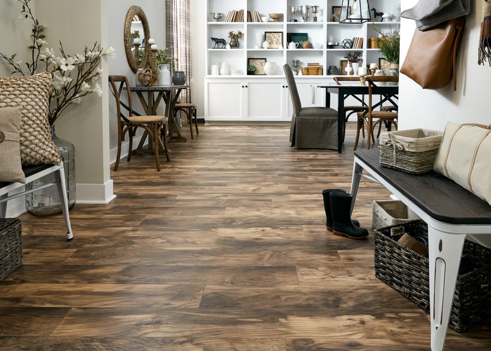 12mm+pad Natural Hackberry 24 Hour Water-Resistant Laminate Flooring in entryway with metal bench open to dining room