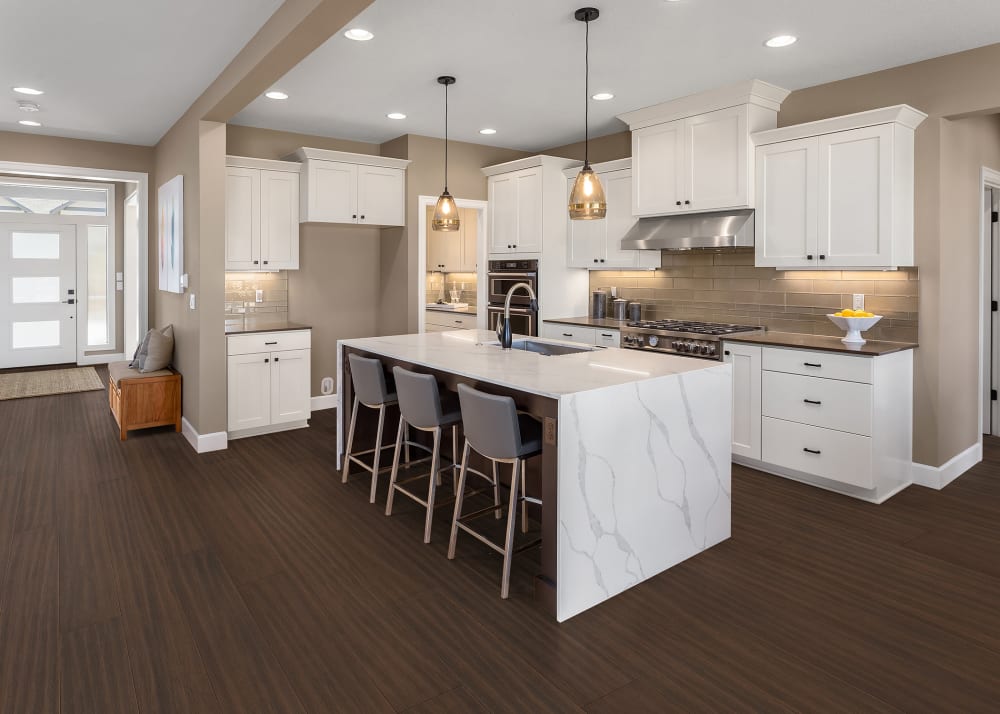 7mm+Pad x 7.5 in Timberline Water-resistant Engineered Bamboo Flooring in kitchen with white cabinets and white marble waterfall island with three bar stools