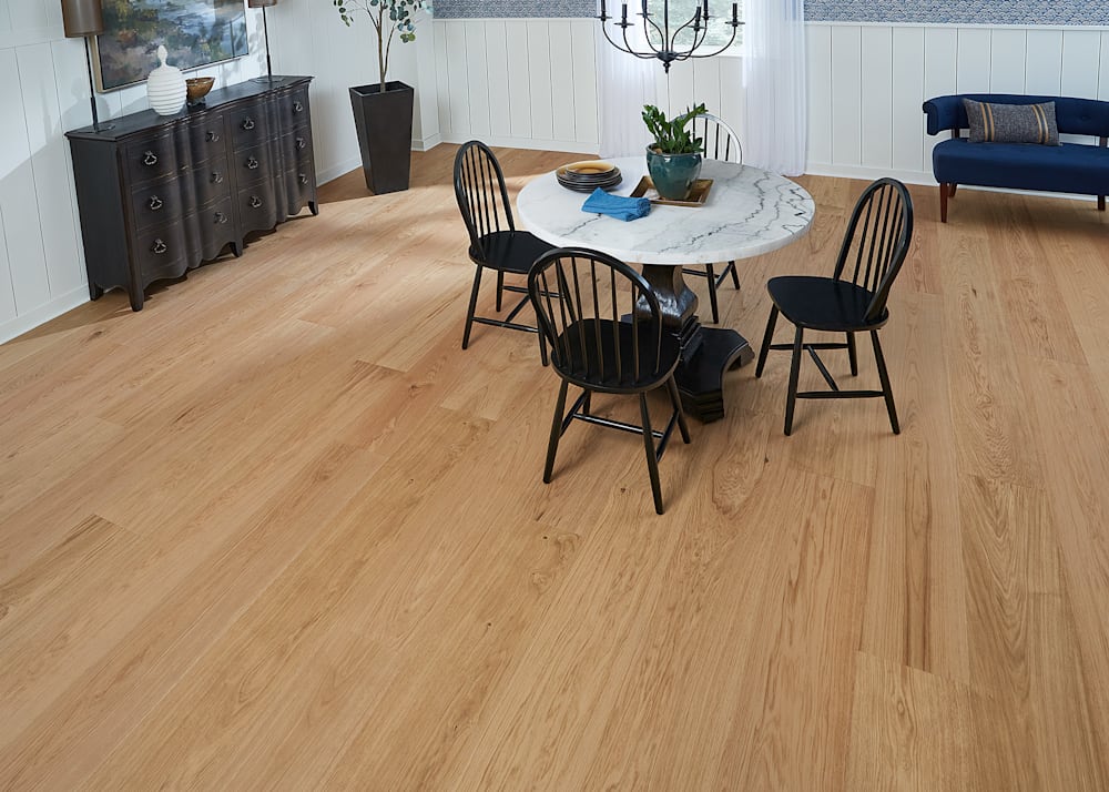 7/16 in x10.67 in Faroe Island White Oak Engineered Hardwood Flooring in dining room with round marble dining table plus black chairs and navy settee plus shiplap on walls