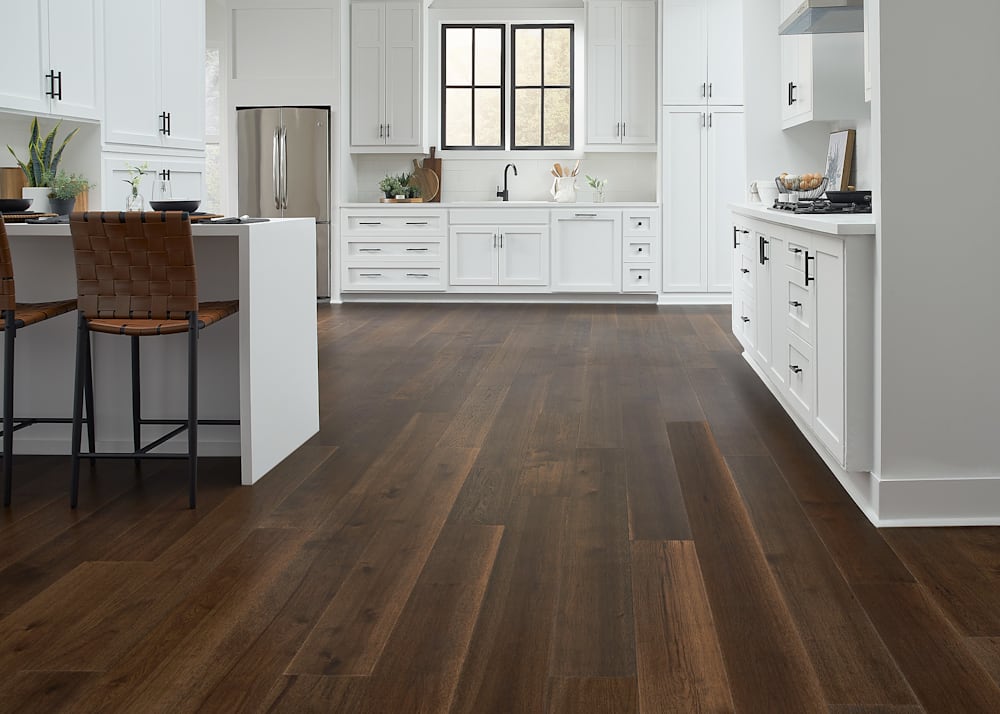 7mm+Pad x 7.48 in Lake Superior Hickory Water-resistant Engineered Hardwood Flooring in kitchen with white cabinets and countertops plus brown leather breakfast stools