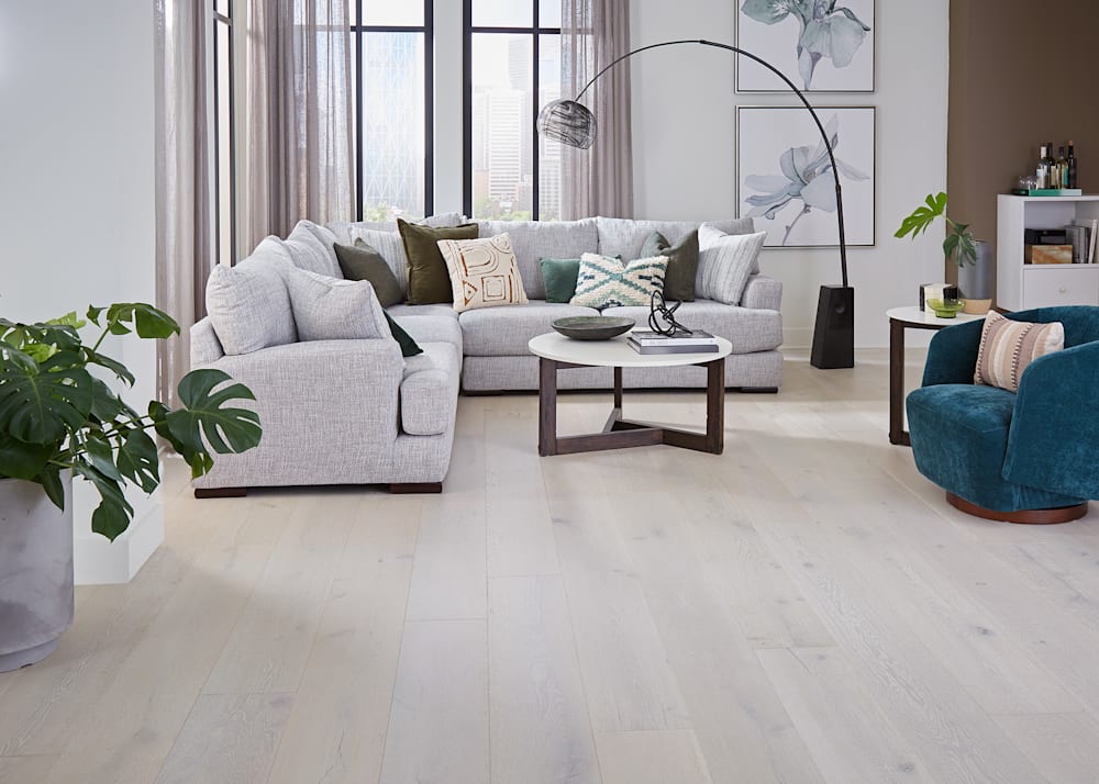 5/8 in x 9.5 in Clearwater Beach White Oak Distressed Engineered Hardwood Flooring in living room with light gray sectional sofa and dark turquoise barrel side chair and brown walls