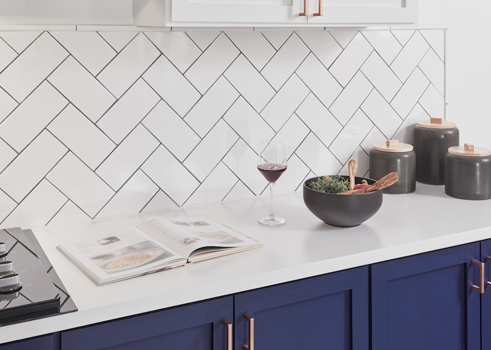 4 in x 8 in Vivid White Subway Ceramic Tile in kitchen with white counters and royal blue lower cabinets
