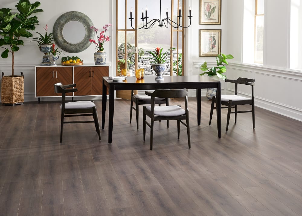 5mm+Pad Seville Maple Rigid Vinyl Plank Flooring in dining room with dark colored table and chairs with light colored cushions open to patio area