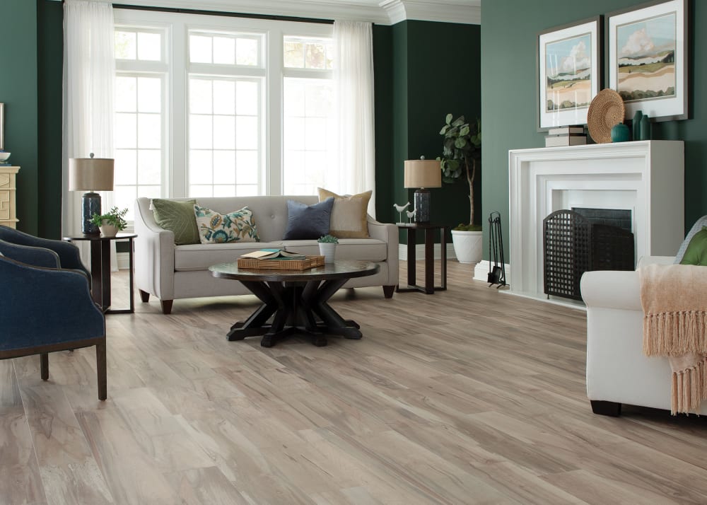 7mm+Pad Preston Peak Maple Hybrid Resilient Flooring in living room with dark green walls and beige sofa