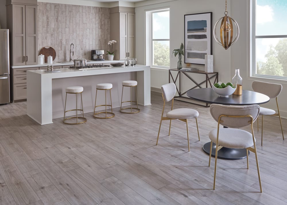 7mm+Pad Gauntlet Gray Oak Hybrid Resilient Flooring in kitchen with large island and gold barstools