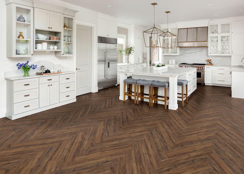 6mm+Pad Cambridge Hickory Rigid Vinyl Plank Flooring in kitchen with white cabinets plus stainless appliances and oversized island with seating for four