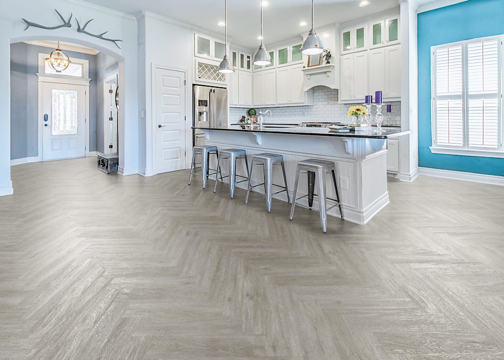 6mm with Pad Chantilly Oak Rigid Vinyl Plank Flooring in kitchen with white cabinets and oversized island with 4 metal bar stools plus turquoise accent wall