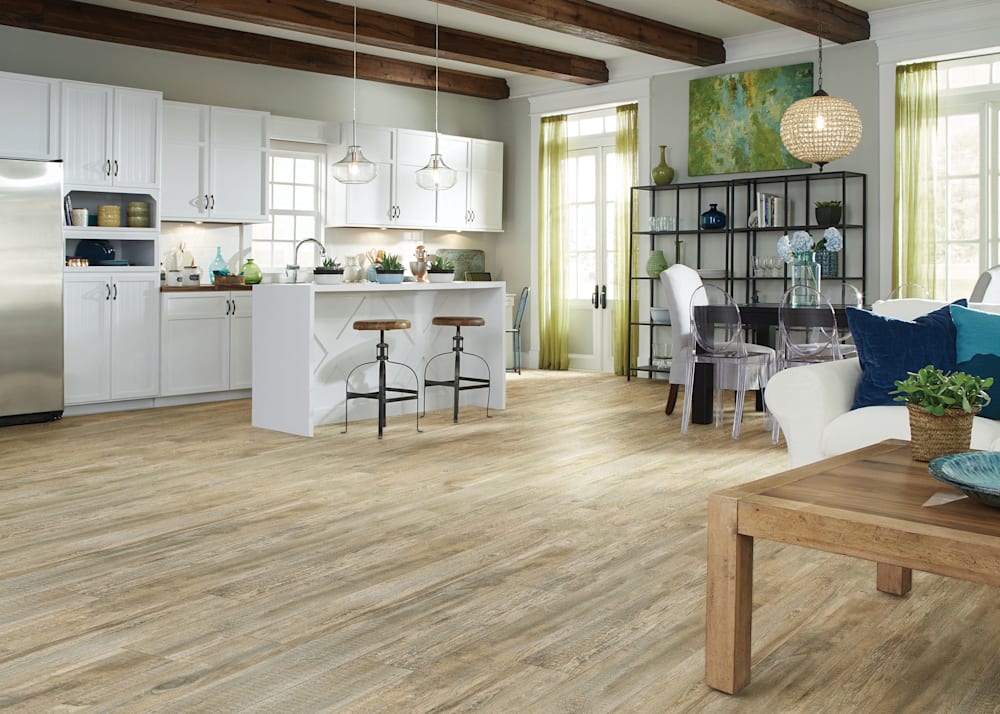 8mm with pad Wagon Wheel Oak Rigid Vinyl Plank Flooring in open concept kitchen dining and living room with white kitchen cabinets and White Island