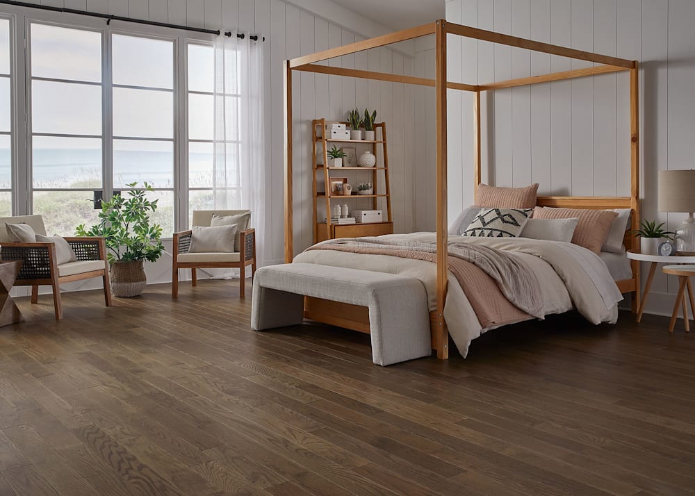 3/4 in. x 4" Arctic Hunter Oak Solid Hardwood Flooring in bedroom with light wood four poster bed with cream and blush bedding plus beige upholstered bench plus accent chairs with light wood arms and cream accent pillows