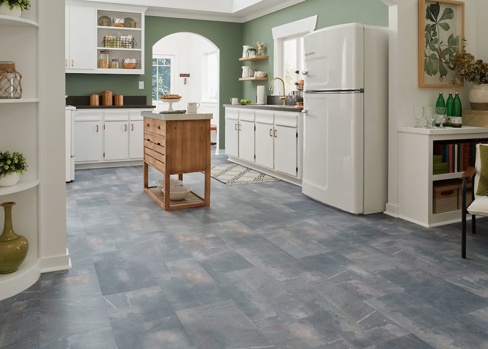 6.5mm with Pad Smithsonian Slate Rigid Vinyl Tile Flooring in open concept kitchen and living room with white kitchen cabinets and appliances plus green walls and built in bookcase with beverage station