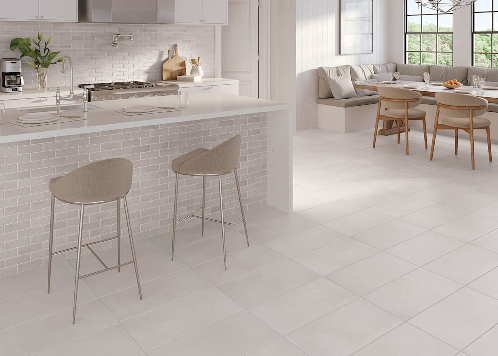 12 in. x 24 in. Lavish Linen Porcelain Stone Look Tile Flooring in kitchen with white cabinets plus white marble waterfall island with beige subway tile and breakfast area with bench seating