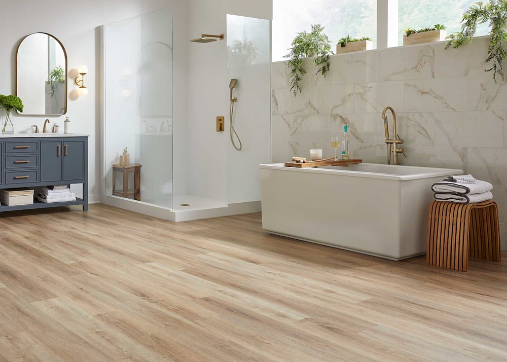 6mm with Pad Island Oak Waterproof Rigid Vinyl Plank Flooring in bathroom with freestanding bathtub plus gray blue vanity and freestanding glass enclosed shower and porcelain tile accent wall