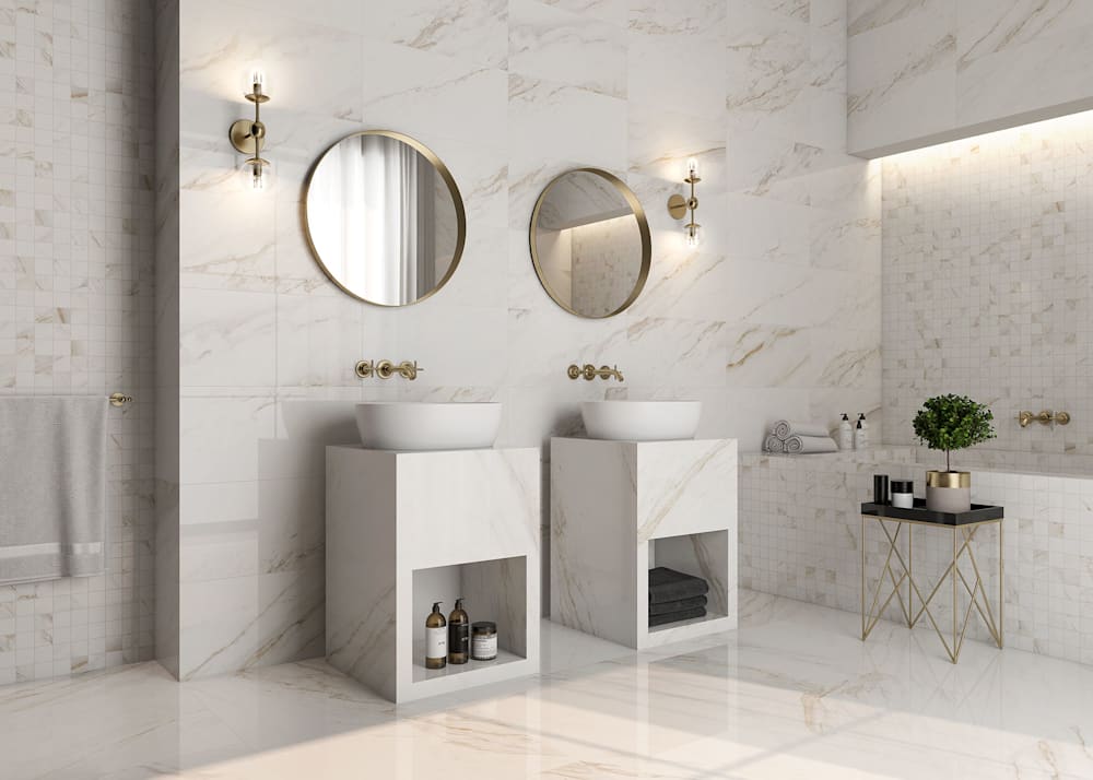 12 in x 24 in Juno Regina Polished Stone Look Porcelain Tile Flooring in bathroom with floor to ceiling tile plus dual vanities with vessel bowls and gold faucets