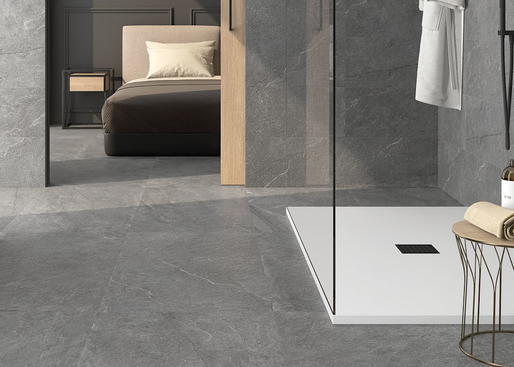 12 in. x 24 in. Quarzo Grigio Stone Look Porcelain Tile Flooring in bathroom on walls and floor plus view into bedroom with tile on floor and gray walls