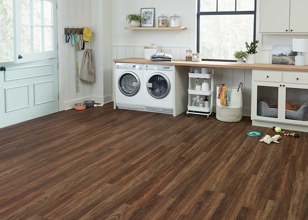 6mm with Pad Vermont Curupay Waterproof Rigid Vinyl Plank Flooring in laundry room with white washer and dryer plus butcher block counter and off white cabinets with built in dog crate