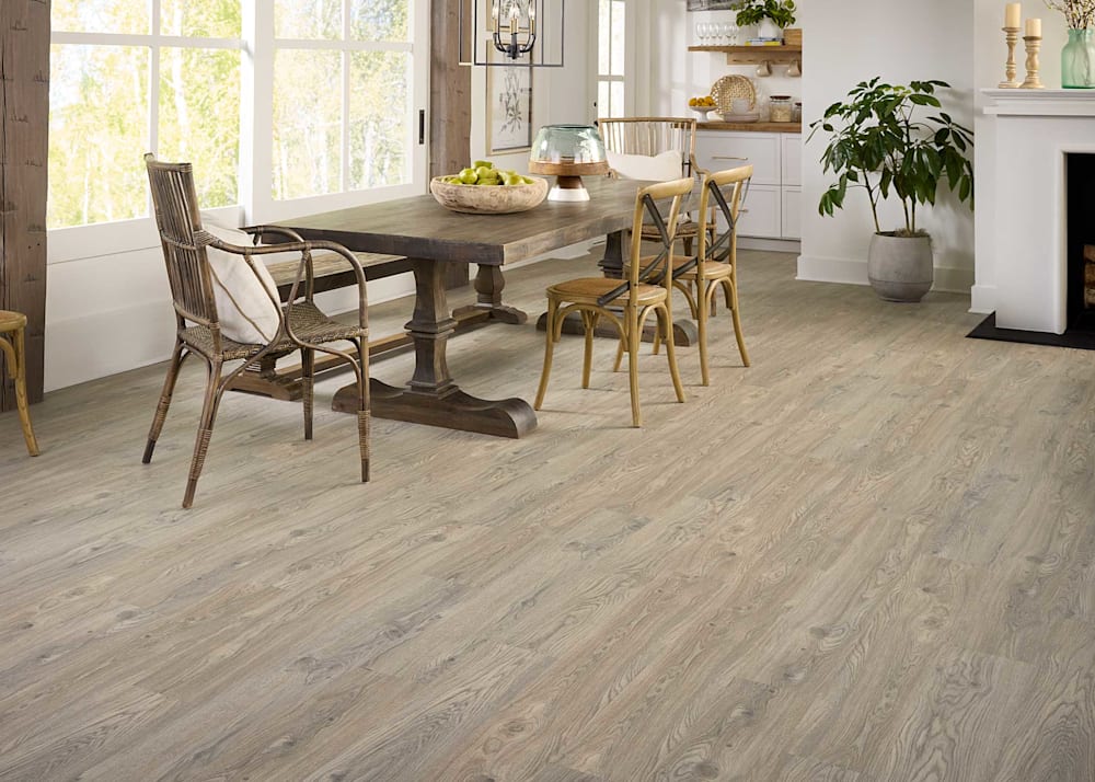 6mm with Pad Rosemont Oak Waterproof Vinyl Plank Flooring in dining room with rustic wood dining table and chairs plus wood floating shelves and fireplace with white mantle